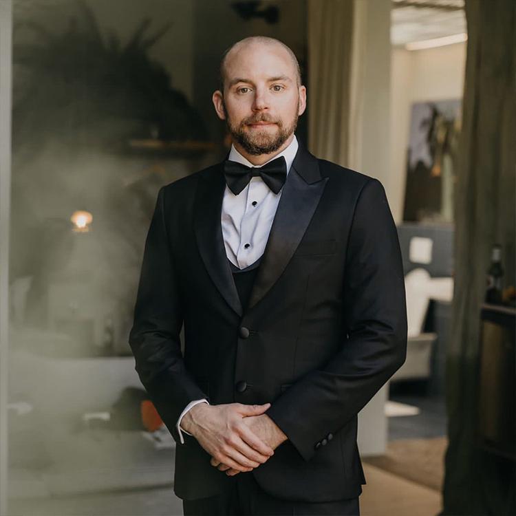 A groom in a black peak lapel tuxedo